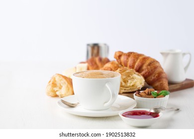 Fresh delicious breakfast with Coffee, crispy croissants, jam on white wooden background. Selective focus. Romantic french weekend concept. Copy space.