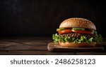 Fresh, delicious burgers with a beef patty, lettuce, onions, tomatoes and cucumbers. A large, fresh hamburger with overflowing cheese filling. On a wooden table isolated on a dark background.