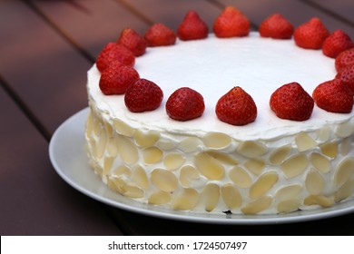 Fresh and delicious homemade summertime theme strawberry, almond and cream cake. Topped with whipped cream, fresh berries and almond slices. Cheerful cake for celebrations like bday or Mother-s day.