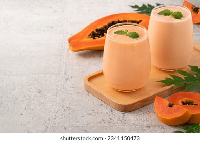 Suave de leche de papaya fresca en vaso de vidrio sobre fondo de mesa gris para el concepto de diseño de frutas tropicales.