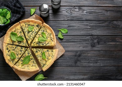 Fresh delicious spinach pie on black wooden table, flat lay. Space for text