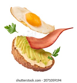 Fresh delicious tasty homemade sandwich with avocado, roasted egg and bacon falling in the air isolated on white background - Shutterstock ID 2071059194