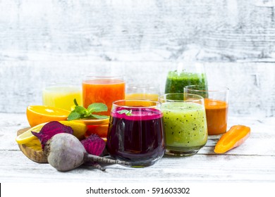 Fresh detox juices from fruit and vegetables in glass bottles on a wooden background
