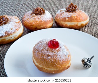 Fresh donuts and silver dreidel for Hanukkah celebration.