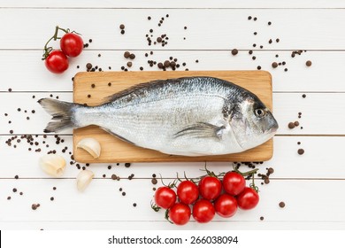 Fresh Dorado Fish On Wooden Cutting Board With Tomatoes