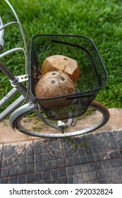 Fresh And Dried Brown Coconuts In A Bicycle Basket With Green Grass At Background, Top View