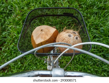 Fresh And Dried Brown Coconuts In A Bicycle Basket With Green Grass At Background, Top View