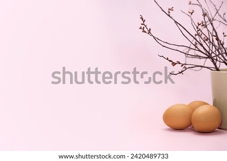 Fresh eggs and a burgeoning branch. Simple empty pink Easter background. Copy space simple pastel rustic background for traditional Easter holiday card