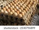 Fresh eggs in cartons stacked at a local market. Poultry farm. Rustic food background. Organic, countryside production of food products. Pile of layers. Tower of eggs.