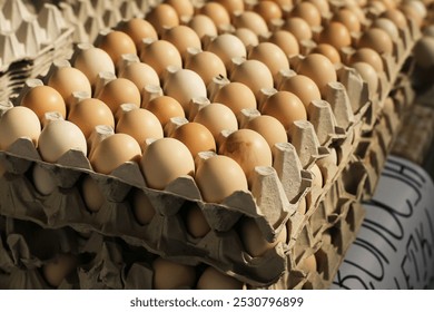 Fresh eggs in cartons stacked at a local market. Poultry farm. Rustic food background. Organic, countryside production of food products. Pile of layers. Tower of eggs. - Powered by Shutterstock