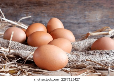 fresh eggs and chicken eggs with dried straw lying on a wooden background table on an organic farm