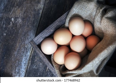 Fresh Eggs in Small Wooden Crate with Canvas on Aged Wooden Table. Fresh Organic Cage Free Chicken Eggs.