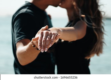 Fresh engaged couple enjoying a romantic engagement day on the beach during a sunny day. Close up on her ring. - Powered by Shutterstock