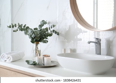 Fresh Eucalyptus Branches And Burning Candles On Countertop In Bathroom