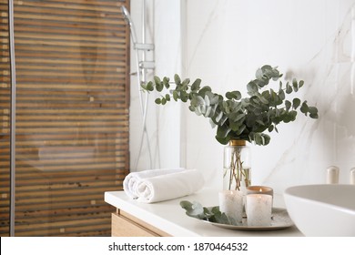 Fresh Eucalyptus Branches And Burning Candles On Countertop In Bathroom