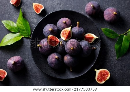 Fresh figs on black plate. Dark background. Close up. Top view.