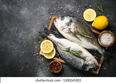 Fresh fish dorado on black stone table with ingredients for cooking. Top view with copy space. - Powered by Shutterstock