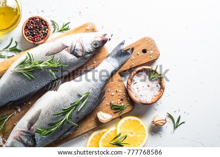 Fresh fish seabass. Raw fish seabass with spices and herbs ingredients for cooking on white background. Top view with copy space.
