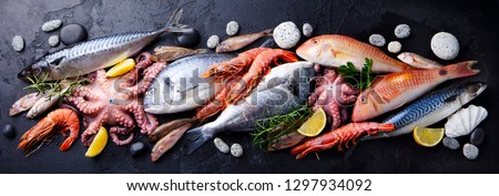 Fresh fish and seafood assortment on black slate background. Top view.
