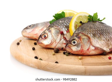 Fresh fishes with lemon, parsley and spice on wooden cutting board isolated on white