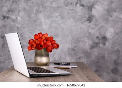 Fresh Flower Composition, Bouquet Of Darwin Hybrid Tulips With Black And White Laptop Computer, Concrete Wall Background. Office Romance Concept. Copy Space, Close Up, Top View, Flat Lay.