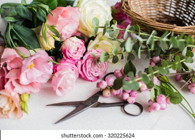 Fresh flowers, leaves, and tools to create a bouquet on a table, florist's workplace. - Shutterstock ID 320225624