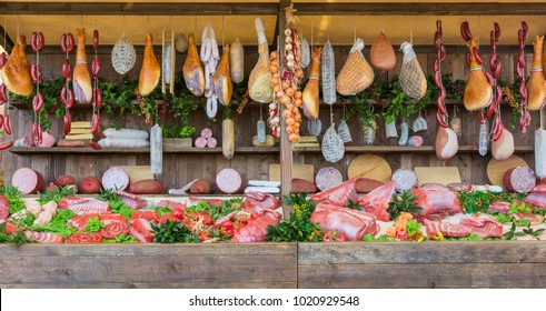 frischer Hintergrund auf dem Lebensmittelmarkt mit rohem Schweinefleisch und vertikal sortierten Salami-Würstchen.