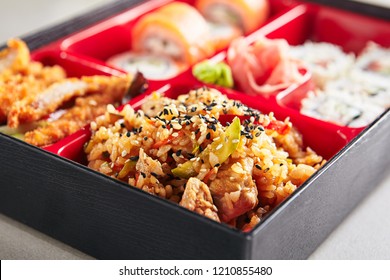 Fresh Food Portion in Japanese Bento Box with Sushi Rolls, Salad and Main Course. Rice and Fried Meat Close Up