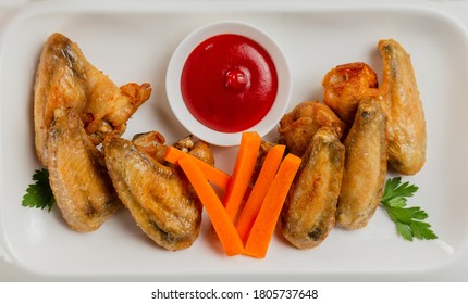 Fresh fried chicken wings on a white plate.