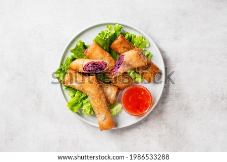 Fresh fried spring rolls stuffed with red cabbage and carrot served with sweet chili dip sauce. Light gray background, top view.