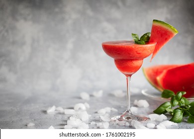 A Fresh Frozen Blended Margarita Drink With Strawberries And Watermelon. The Drink Is Garnished With Basil Leaves And Watermelon. On Ice Scattered Gray Background.Horizontal, Copy Space Room For Text.