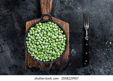 Fresh Frozen green peas in a pan. Black background. Top view