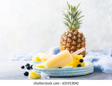 Fresh Frozen Juice Ice Cream, Pineapple Popsicles With Blueberries On Light Blue Plate. Summer Food Concept With Copy Space.