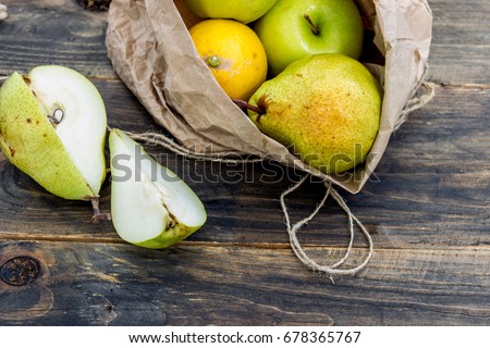 Fresh fruit in a craft bag on a dark background. Apple, pear and lemon as ingredients for drinks. Concept of healthy eating.