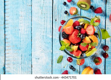 Fresh Fruit Salad With Various Kind Of Berry And Citrus Fruit Served In Glass Bowl, Placed On Wooden Table. Shot From Aerial View, Copyspace For Text