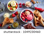 Fresh fruit with scoops of creamy speciality ice cream in assorted flavors with raspberry, berry, blueberry, strawberry, walnut , pistachio, chocolate, sugar cones and a scoop for serving from above