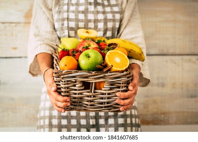 Fresh fruits bucket holded by adult woman with wall background - concept of weight loss and fruit store commerce - agriculture and farmer job lifestyle