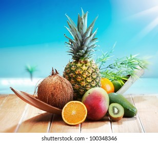 Fresh Fruits on the beach at a deck in front of an island with a palm. Assorted tropical fruits, orange,Ananas or pineapple, lime,mango and avocado. - Powered by Shutterstock