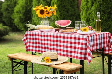 Fresh fruits, pie, bottle of drink and vase with sunflowers on table in garden - Powered by Shutterstock