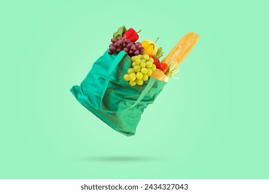 Fresh fruits and vegetables grocery product in green reusable shopping bag isolated on green background - Powered by Shutterstock