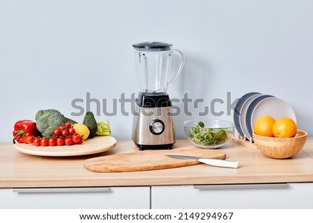 Fresh fruits and vegetables with modern automatically mixer on table for making smoothie and juice