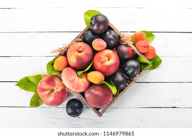 Fresh fruits in a wooden box. Apricot, peach, nectarine, plum. On a wooden background. Top view. Free space for your text. - Powered by Shutterstock