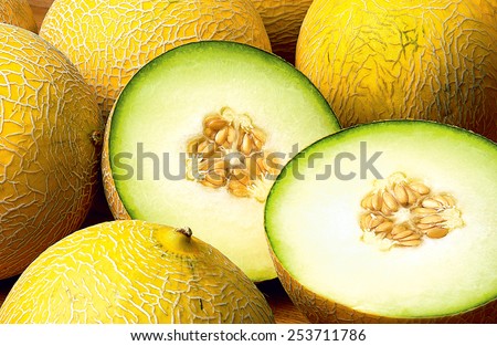Fresh Galia Melons displayed in a group close up with one cut through center to show seed detail                        