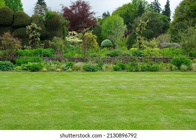 Fresh garden with a mowed lawn, colourful flower bed and leafy trees - Shutterstock ID 2130896792