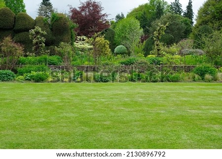 Fresh garden with a mowed lawn, colourful flower bed and leafy trees