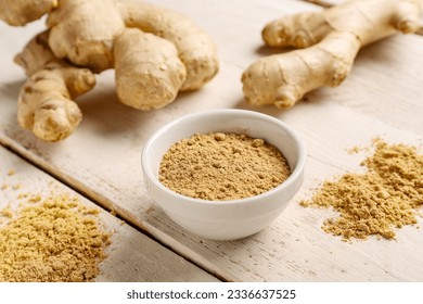 Fresh ginger roots and bowl with dried powder on white wooden background - Powered by Shutterstock