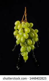 Fresh grape with water or juice splashes, isolated on a black background. Fruit levitation, flying food