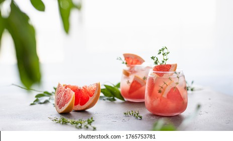 Fresh grapefruit cocktail. Fresh summer cocktail with grapefruit, thyme and ice cubes. Glass of grapefruit lemonade. Side view, menu, recipe