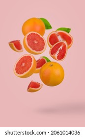Fresh grapefruit sliced on pastel pink background. Minimal fruit concept. Vitamins, healthy diet concept. Sliced and whole grapefruit floating in the air. Creative concept with flying fruits.