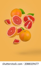 Fresh grapefruit sliced on yellow background. Minimal fruit concept. Vitamins, healthy diet concept. Sliced and whole grapefruit floating in the air. Creative concept with flying fruits.